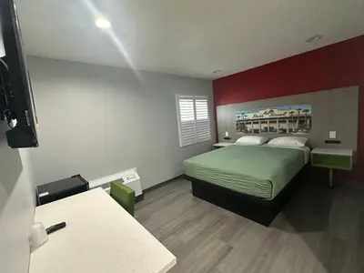 a bedroom with a bed and a red wall at Hi-Way Host Motel in Pasadena