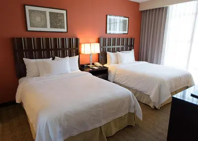 two beds in a hotel room with red walls at Embassy Suites Ontario - Airport in Ontario