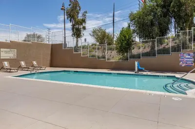 a swimming pool with two chairs and a fence at Hampton Inn Norco/Corona in Norco