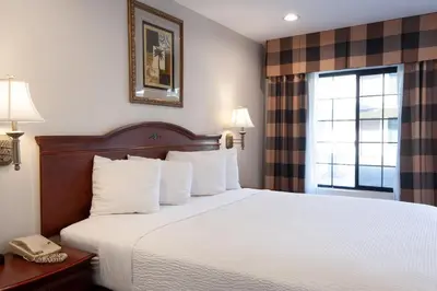 a hotel room with a bed with white sheets and a window at Studio City Court Yard Hotel in Los Angeles