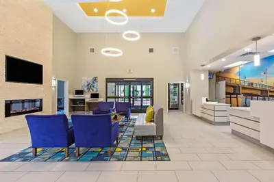 a lobby with blue chairs and a couch and a tv at La Quinta by Wyndham NE Long Beach/Cypress in Hawaiian Gardens