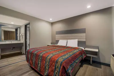 a bedroom with a large bed and a sink at Rodeway Inn San Bernardino - Colton in San Bernardino