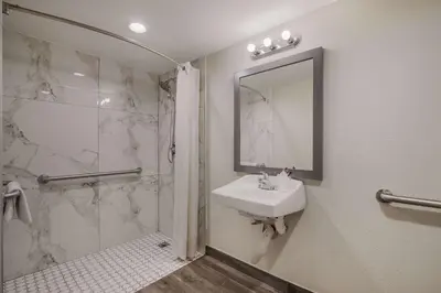 a bathroom with a sink and a shower and a mirror at Rodeway Inn San Bernardino - Colton in San Bernardino