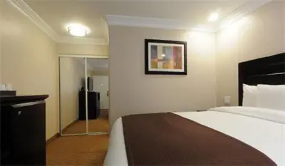 a hotel room with a bed and a mirror at Raincross Hotel Riverside in Riverside
