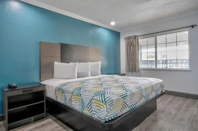a bedroom with a bed and a blue wall at Studio 6 Suites San Bernardino, CA in San Bernardino