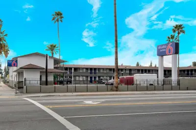 an empty street in front of a building with palm trees at Studio 6 Suites San Bernardino, CA in San Bernardino