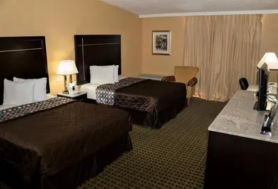 a hotel room with two beds and a television at California Inn Barstow in Barstow