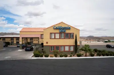 a carolina inn building with a parking lot at California Inn Barstow in Barstow