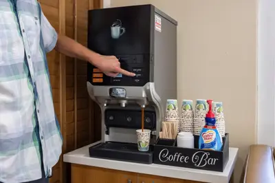 a man is standing next to a coffee machine at Del Sol Inn Anaheim in Anaheim