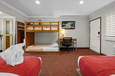 a bedroom with two bunk beds and a desk at Del Sol Inn Anaheim in Anaheim