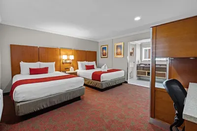 a hotel room with two beds and a desk at Del Sol Inn Anaheim in Anaheim
