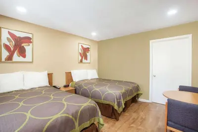 a hotel room with two beds and a table at Super 8 by Wyndham Redlands/San Bernardino in Redlands