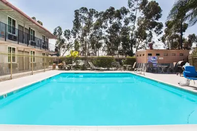 a swimming pool with chairs and a house at Super 8 by Wyndham Redlands/San Bernardino in Redlands