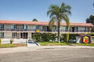a building with a palm tree in front of it at Super 8 by Wyndham Redlands/San Bernardino in Redlands
