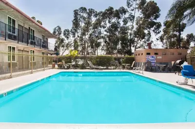 a swimming pool with chairs and a house at Super 8 by Wyndham Redlands/San Bernardino in Redlands
