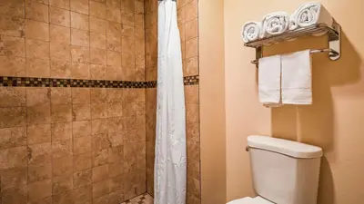 a bathroom with a shower with a toilet and a shower curtain at SureStay Hotel by Best Western Tehachapi in Tehachapi