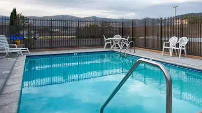 a swimming pool with chairs and a table at SureStay Hotel by Best Western Tehachapi in Tehachapi