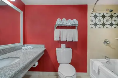 a bathroom with a white toilet and a red wall at SureStay Hotel by Best Western Camarillo in Camarillo