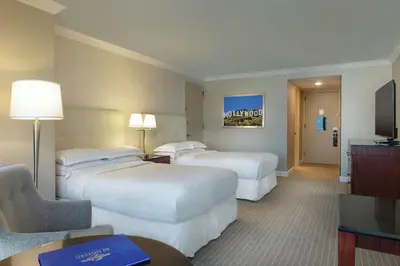a hotel room with three beds and a television at Hilton Los Angeles-Universal City in Los Angeles