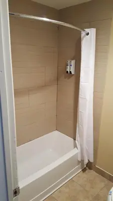 a shower with a white tub in a bathroom at Anaheim Astoria Inn & Suites in Anaheim