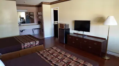 a hotel room with a bed and a flat screen tv at Anaheim Astoria Inn & Suites in Anaheim