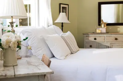 a bedroom with a bed with white pillows and a table at Channel Road Inn, A Four Sisters Inn in Los Angeles