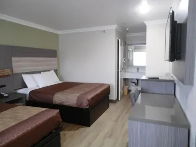 a small hotel room with two beds and a sink at Americas Best Value Inn-Rialto in Rialto