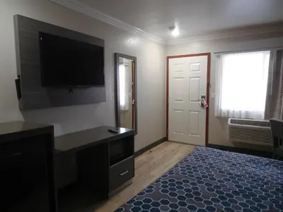 a bedroom with a flat screen tv and a bed at Americas Best Value Inn-Rialto in Rialto