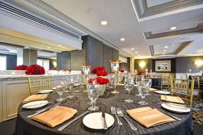 a dining room with a table with glasses and red flowers at Hilton Checkers Los Angeles in Los Angeles