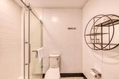 a white bathroom with a shower and a toilet at Casa Via Mar Inn, an Ascend Collection Hotel in Port Hueneme