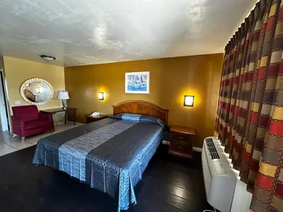 a bedroom with a bed and a chair in a room at Sunpark Inn & Suites in San Bernardino