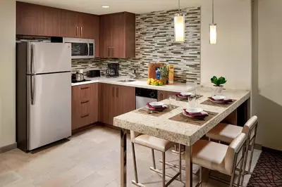 a kitchen with a refrigerator and a table with chairs at Residence Inn by Marriott at Anaheim Resort/Convention Center in Anaheim