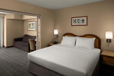 a hotel room with a large bed and a couch at Anaheim Portofino Inn & Suites in Anaheim
