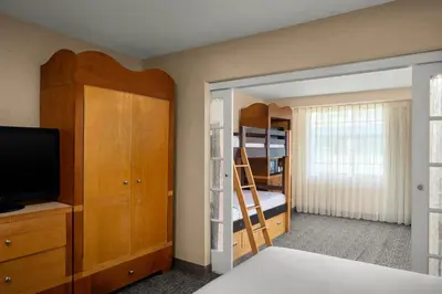 a bedroom with a bed and a tv and bunk beds at Anaheim Portofino Inn & Suites in Anaheim