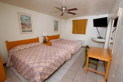 a bedroom with two beds and a table and a television at Mission Bell Motel in Ventura