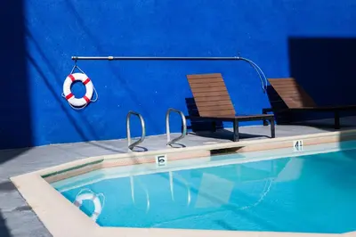 a swimming pool with two chairs and a lifesaver at Anaheim Carriage Inn in Anaheim