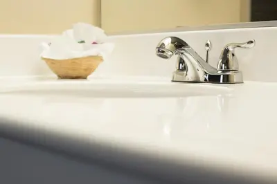 a bathroom sink with a faucet and a basket on it at Anaheim Carriage Inn in Anaheim