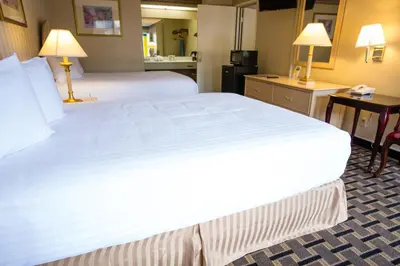 a large white bed in a hotel room at Anaheim Carriage Inn in Anaheim