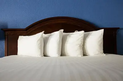 a bed with white pillows against a blue wall at Anaheim Carriage Inn in Anaheim