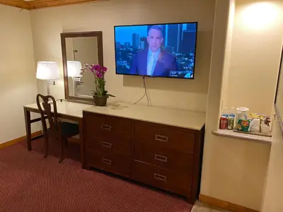 a hotel room with a desk with a television on the wall at Best Inn Rosemead in Rosemead