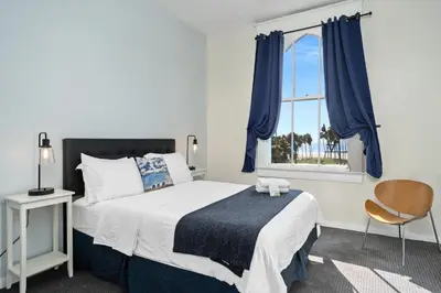 a bedroom with a bed and a window with blue curtains at Samesun Venice Beach Hotel & Hostel in Los Angeles