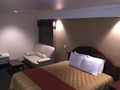 a hotel room with a bed and a chair at Ontario Inn & Suites in Montclair