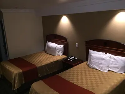 a hotel room with two beds with white pillows at Ontario Inn & Suites in Montclair