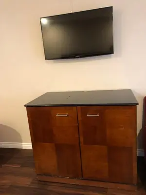 a television on a wall above a wooden cabinet at American Inn in Ontario