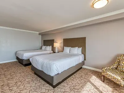 a hotel room with two beds and a chair at Amanzi Hotel, an Ascend Collection Hotel in Ventura