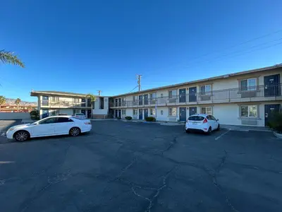 two white cars parked in a parking lot in front of a building at Studio 6 Mojave, CA - Airport in Mojave