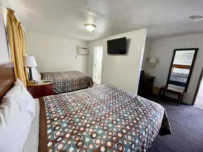 a hotel room with two beds and a flat screen tv at Desert Inn in Mojave