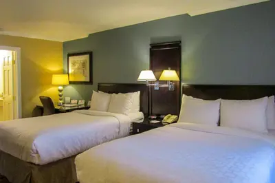two beds in a hotel room with two lamps at Clarion Inn Near China Lake Naval Station in Ridgecrest