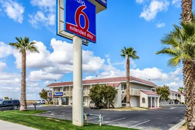 a sign in front of a hotel with palm trees at Studio 6-Buttonwillow, CA in Buttonwillow