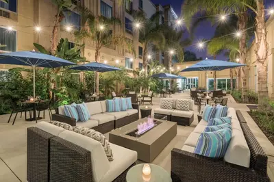 an outdoor patio with couches and umbrellas at night at DoubleTree by Hilton Los Angeles/Commerce in Commerce